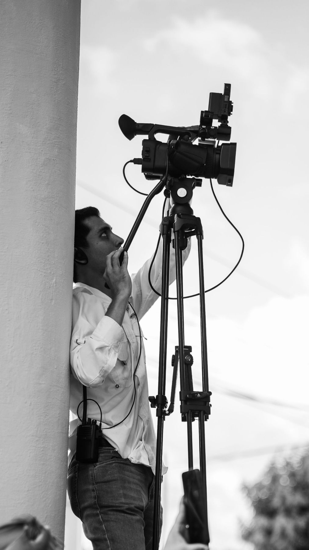 Camera operator on a tripod, talking on a radio