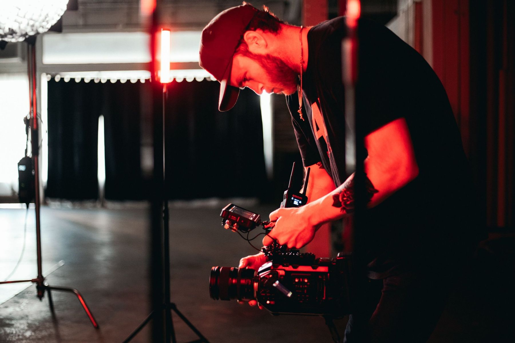 Camera operator setting up under red practical lights